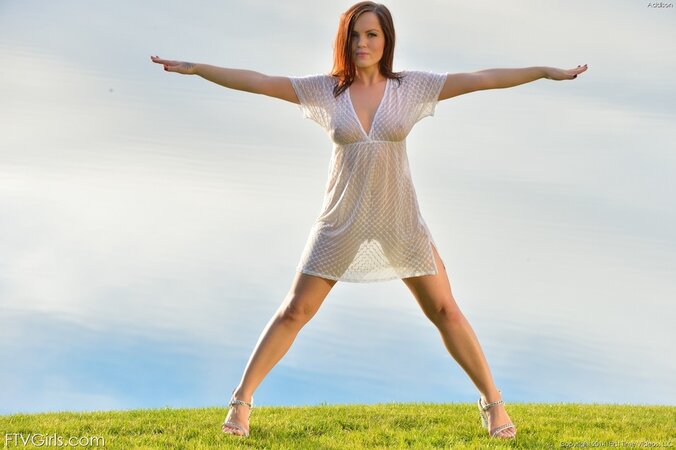 One sexy redhead takes off her dress while near a lake