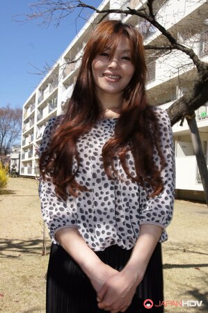 Eastern redhead in a shirt poses for photographer against a apartment building