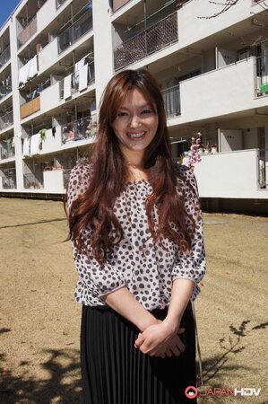 Eastern redhead in a shirt poses for photographer against a apartment building
