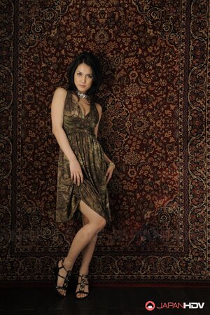 Brunette cutie in a sexy dress stands up against the carpet on the wall