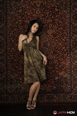 Brunette cutie in a sexy dress stands up against the carpet on the wall