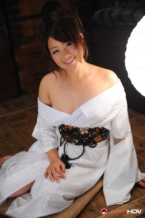 Cute young Japanese woman in a kimono participates in erotic photo session