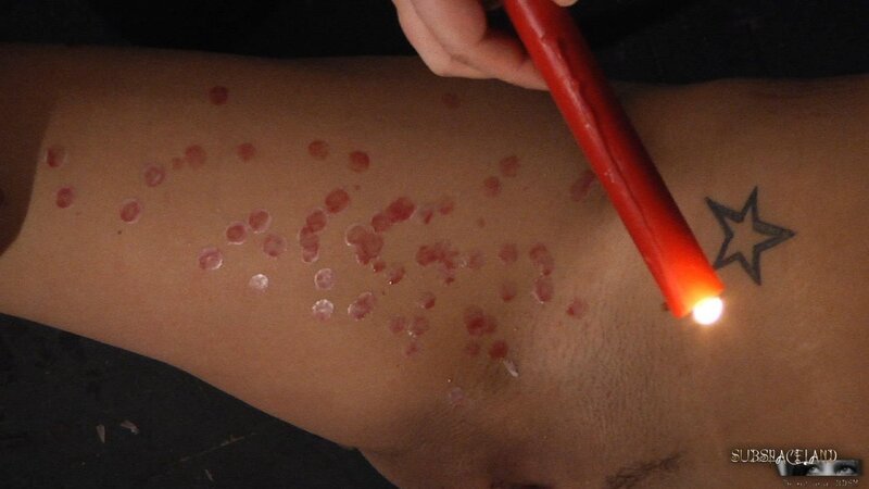 Dominant man lights a candle and pours girl's slender body with hot wax